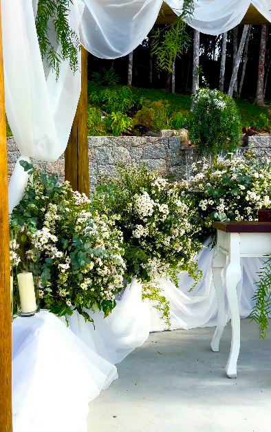 Decoração de cerimônia com gazebo rústico, folhagens brancas e tecidos fluidos
